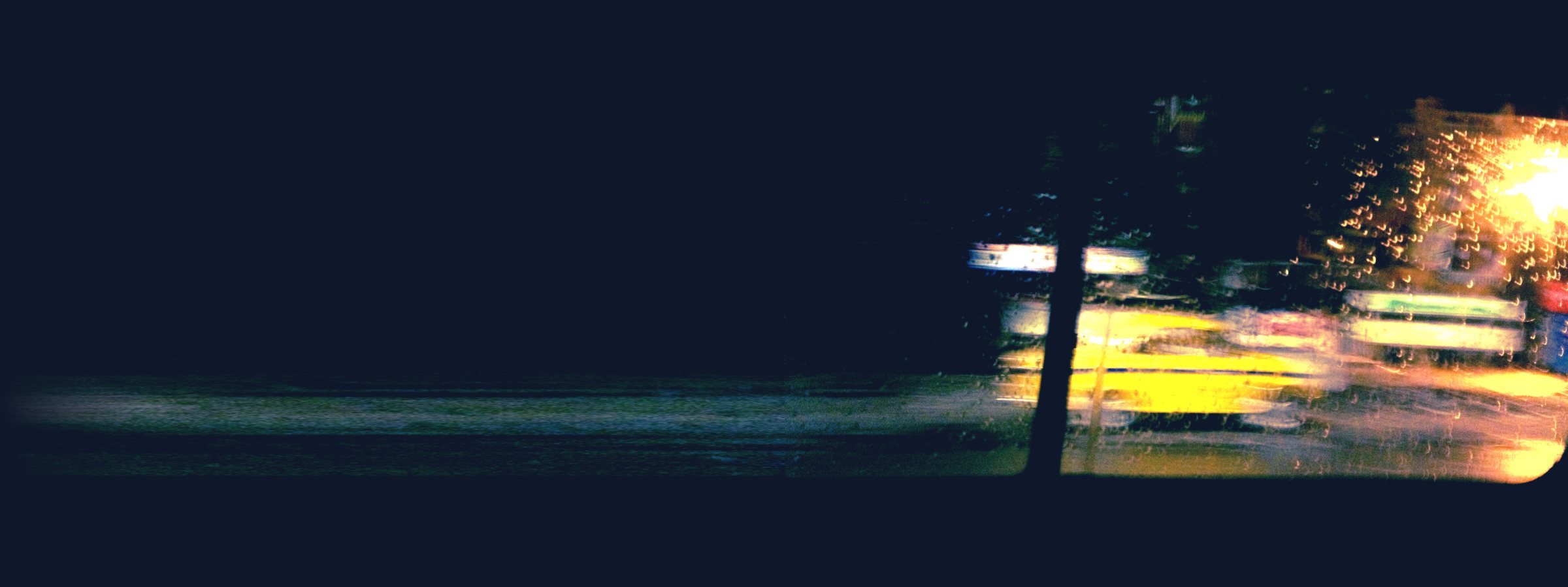Un taxi jaune filé dans la nuit, vu à travers une vitre de voiture mouillée, Kolkata